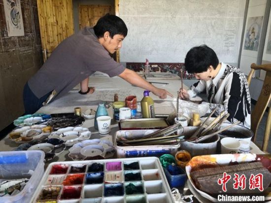 圖為2020年8月下旬，敦煌“80后”畫家張杰龍(左)在為云南麗江“學(xué)生”莫北講解敦煌壁畫的繪畫技巧?！●T志軍 攝