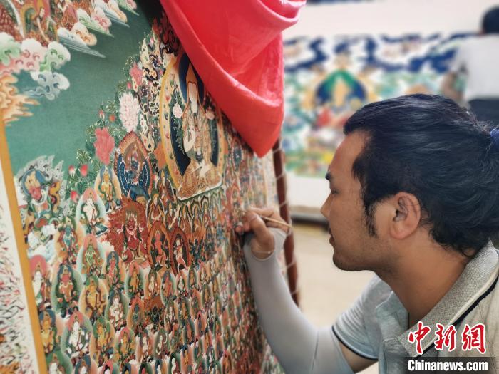圖為更登才讓的徒弟繪畫唐卡?！?zhí)砀?攝