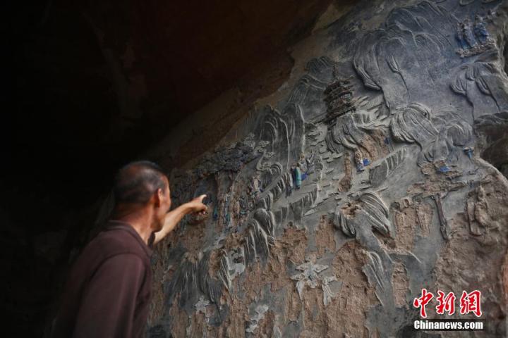 7月15日，甘肅省平?jīng)鍪袥艽h百里石窟長廊羅漢洞石窟內(nèi)，該窟文保員郭建平介紹窟內(nèi)石刻彩繪壁畫。郭建平家中三代人曾自發(fā)保護羅漢洞石窟。羅漢洞石窟遺存40余個窟龕，以北魏至清代風(fēng)格為主。中新社記者 李亞龍 攝