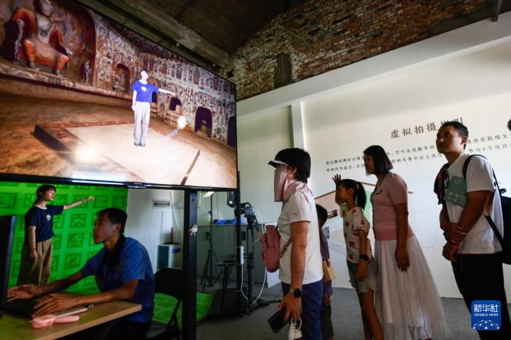 7月22日，游客體驗“尋境敦煌——數(shù)字敦煌沉浸展”后，在虛擬演播廳拍攝一段真人與洞窟虛擬場景交互的視頻。新華社記者 郎兵兵 攝</p>
<p>