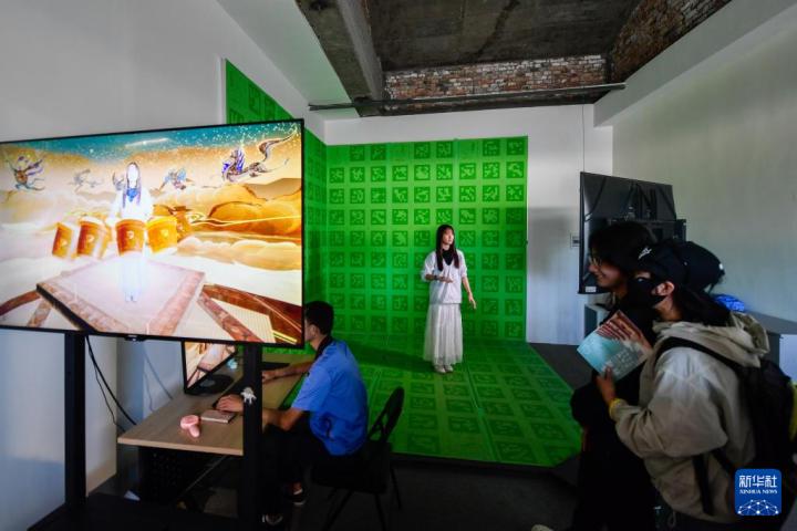 7月22日，游客體驗“尋境敦煌——數(shù)字敦煌沉浸展”后，在虛擬演播廳拍攝一段真人與洞窟虛擬場景交互的視頻。新華社記者 郎兵兵 攝</p>
<p>